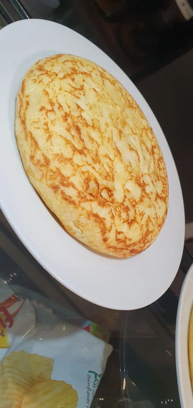 Tortilla de patata entera dorada en un plato blanco